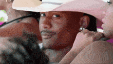 a man in a pink cowboy hat is sitting next to a woman in a pink dress .