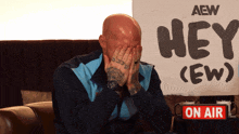 a man covering his face in front of a sign that says " hey ( ew ) "
