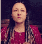 a woman with dreadlocks and a red shirt looks at the camera