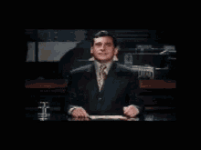 a man in a suit and tie is laughing while sitting at a table