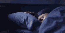 a man is laying in bed with a blue blanket and pillow .