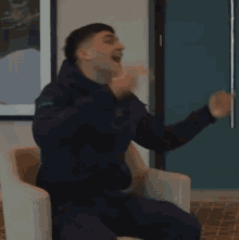 a blurry picture of a man sitting in a chair with the letter o on his jacket