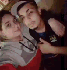 a man and a woman are posing for a picture together . the man is wearing a hat .