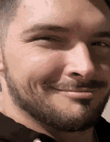 a man with a beard and mustache smiles for the camera