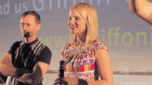 a woman is holding a microphone in front of a screen that says www.griffon