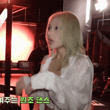 a woman in a white shirt is standing in a room with korean writing on the wall behind her