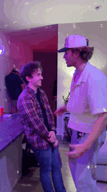 two men standing next to each other in a room with purple lights .