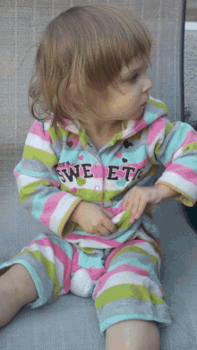 a little girl is wearing a striped outfit that says sweet on it