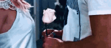 a man is giving a rose to a woman in a blue shirt .