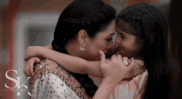 a woman is hugging a little girl with the letter sk in the corner