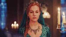 a woman in a green dress with a necklace and a tiara