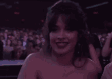 a woman in a blue dress is waving her hand in front of a crowd in a dark room .