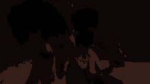 a man in a baseball cap holds a woman 's hand in the dark