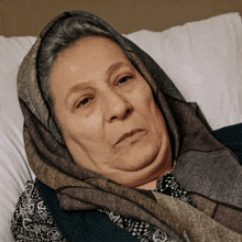 a woman with a scarf around her head is laying in bed