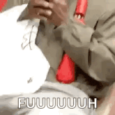 a man in a suit and tie is sitting down holding a piece of paper and a cell phone .