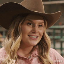 a woman wearing a cowboy hat and a pink shirt with netflix written on the bottom right