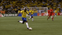 a soccer player wearing a yellow jersey with the number 18 on it kicks the ball