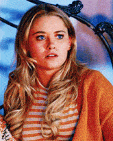 a woman wearing a striped shirt and an orange cardigan