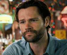 a man with a beard wearing a blue shirt is looking at the camera