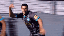 a soccer player in a gray and blue jersey is celebrating a goal .