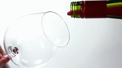 a bottle of red wine is poured into a wine glass