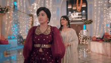 a woman in a purple dress is standing next to another woman in a white dress .