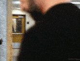 a man in a black shirt is standing in front of a door with the words millythegoat at the bottom
