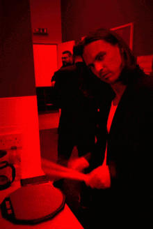 a man in a suit is standing in a dark room with a red light behind him that says ikea