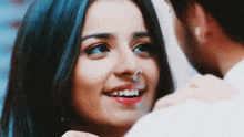 a woman is smiling while looking at a man 's face .