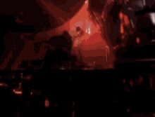a man is playing drums on a stage in a dark room .