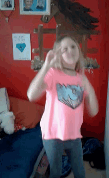 a girl in a pink shirt dancing in front of a red wall