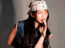 a woman wearing a louis vuitton head scarf and a denim vest