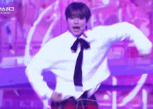 a man wearing a white shirt and tie is dancing on a stage .