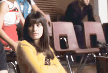 a woman in a yellow shirt is sitting in a chair