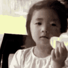 a little girl is holding a piece of bread in her hand and making a funny face .