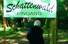 a sign that says schattenwald eingang is in the woods