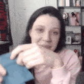 a woman in a pink sweater is holding a piece of paper in her hands .