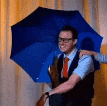 a man in a suit and tie is holding an umbrella over his head .