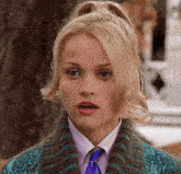 a woman wearing a tie and sweater looks surprised