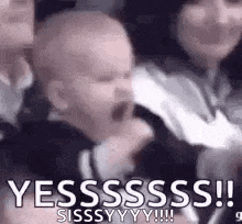 a baby is screaming in a crowd of people while a woman holds it .