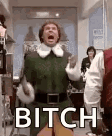 a man in a green elf costume is screaming and saying bitch while standing in a kitchen .