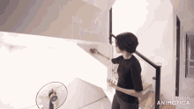 a woman in a black shirt is standing next to a fan and stairs made in animatica