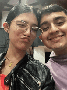 a man and a woman are posing for a picture and the woman is wearing a necklace that says ' a '