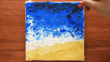 a person is painting a picture of a beach with blue and white paint