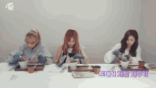 three women are sitting at a table with a twice logo on the top