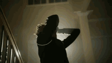 a person is standing on a set of stairs in a dark room with their arms outstretched