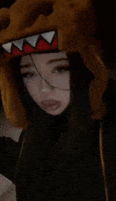 a girl wearing a shark hat is taking a picture of herself with her phone .