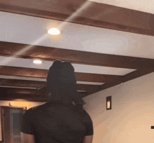a person in a black shirt is standing in a room with wooden beams on the ceiling