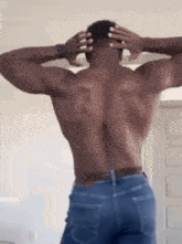 the back of a shirtless man in blue jeans is shown .