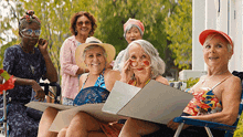 a group of older women are posing for a picture while sitting on a porch .